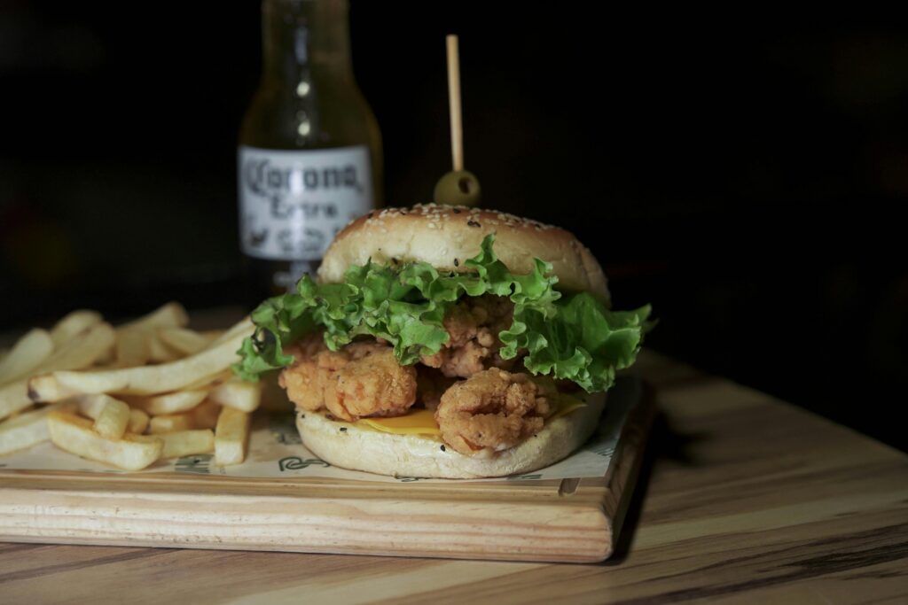 Delicious fried chicken burger with lettuce, served with crispy fries and a beer.
