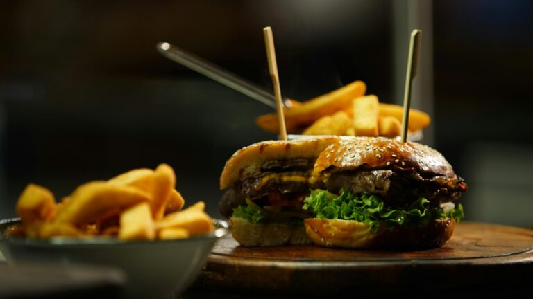 Close-up of a juicy cheeseburger served with crispy fries on a wooden board.
